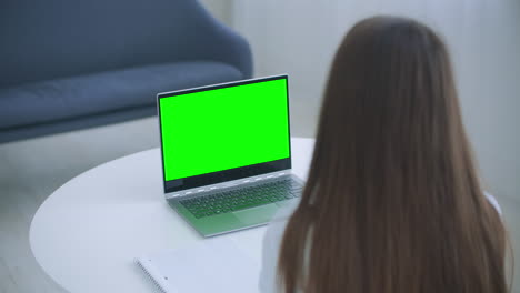 Medical-worker-a-woman-in-a-white-coat-uses-a-tablet-in-the-office-at-the-Desk-chromakey-on-the-tablet-screen-a-view-over-her-shoulder.-doctor-talking-to-laptop-with-green-screen.